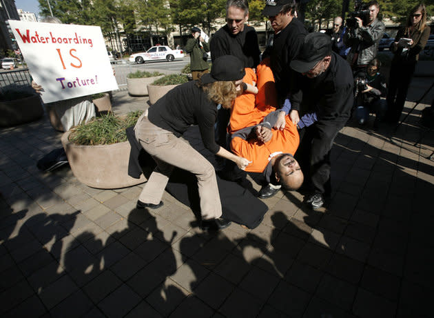 Personas bajando al manifestante Maboud Ebrahimzadeh hasta la tabla de la simulación del submarino, fuera del Departamento de Justicia en Washington, el 5 de noviembre de 2007.