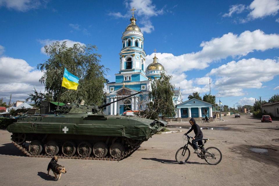 A boy rides a bicycle near an armored tank with a Ukrainian flag in the town of Izyum on Sept. 19.<span class="copyright">Oleksii Chumachenko—SOPA Images/LightRocket/ Getty Images</span>