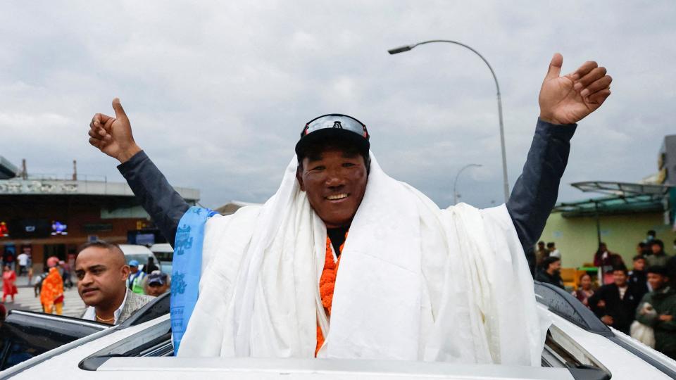 Kami Rita Sherpa waves to supporters from the top of car after arriving back at base camp after his 28th climb in 2023