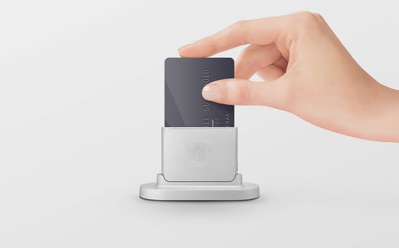 A hand placing a credit card into Shopify's chip and swipe card reader.