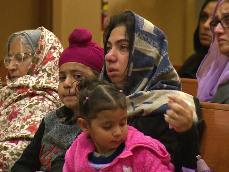 Navjeet Kaur Sodhi, the wife of of Karanjot Singh Sodhi, who died in a bus crash east of Merritt B.C. on Christmas Eve, attends his funeral with their two children and his mother in Delta on Saturday. (Sohrab Sandhu/CBC - image credit)