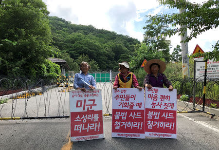 Villagers holding banners bearing their demands stand during an anti-THAAD protest near an entrance of a golf course where a Terminal High Altitude Area Defense (THAAD) system is deployed, in Seongju, South Korea, July 4, 2018. REUTERS/Kim Jeong-min