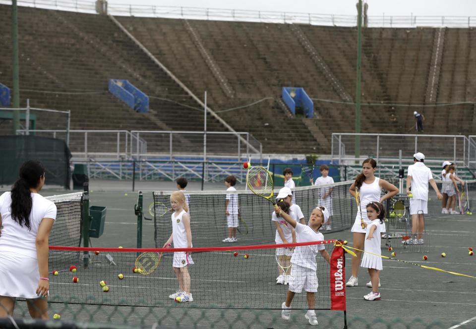 In this Tuesday, July 2, 2013 photo, kids learn tennis on courts in front of the stadium at the West Side Tennis Club in the Queens section of New York. The Beatles. The Rolling Stones. Frank Sinatra. Jimi Hendrix. Bob Dylan. They’ve all held court at the more than century-old West Side Tennis Club in Queens’ Forest Hills neighborhood - for six decades the site of the U.S. Open Tennis Championships. Plans are now in the works for the grassy lawn to come alive again with the sound of music, starting with a concert featuring the British band Mumford & Sons, to be followed by a lineup of world-class musicians. (AP Photo/Seth Wenig)