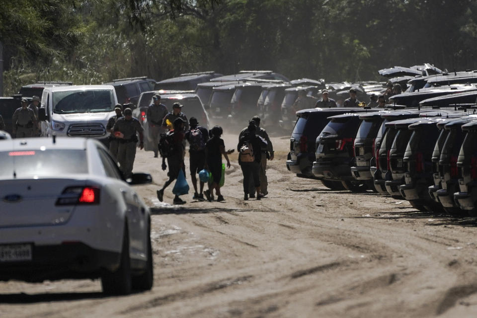 Cuban nationals, center, walk near Texas Department of Public Safety officials and vehicles on a road along the Rio Grande after crossing the river while seeking asylum, Thursday, Sept. 23, 2021, in Del Rio, Texas. (AP Photo/Julio Cortez)