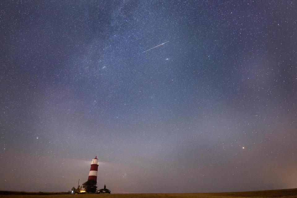 A meteor during the Perseid meteor shower seen over Happisburgh lighthouse in Norfolk, England. / Credit: Joe Giddens/PA Images via Getty Images