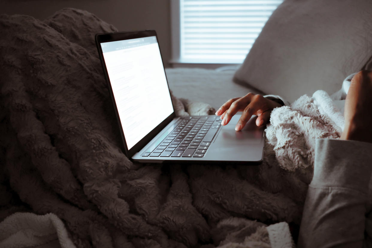 Close-up of unrecognizable black woman working on laptop in bed