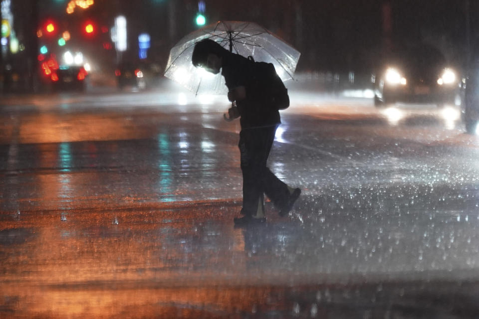 A person holds an umbrella against strong wind and rain as he walks on a street Friday, June 2, 2023, in Tokyo, as a tropical storm was approaching. (AP Photo/Eugene Hoshiko)