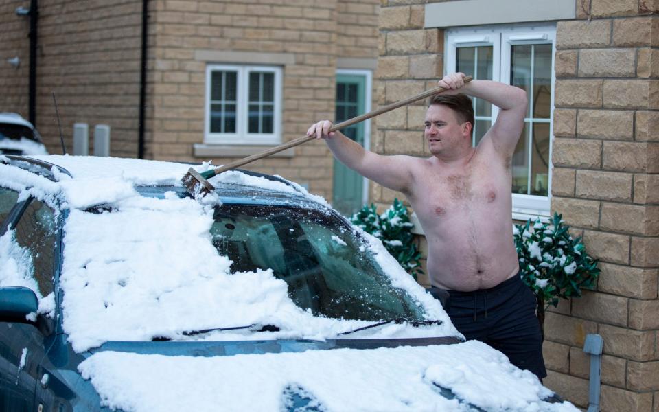 A topless man clears snow from his car in Wakefield - SplashNews.com/Splash News