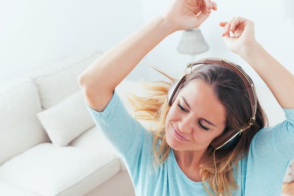 A girl wearing headphones smiling and dancing.