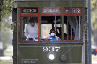 FILE - In this March 19, 2020 file photo, a streetcar conductor wears a mask due to the coronavirus pandemic as she runs her route on St. Charles Ave. in New Orleans. Where political divides marred early recovery efforts after Hurricane Katrina in 2005, Louisiana is showing rare political unity in the fight against the new coronavirus. (AP Photo/Gerald Herbert, File)