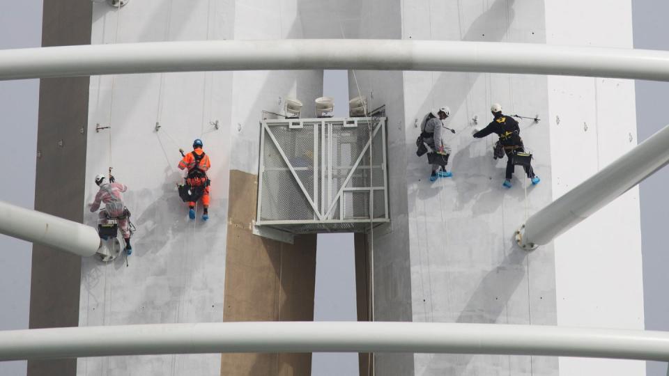 Spezialisten klettern an der Außenseite des «Spinnaker Towers» und streichen dabei den Aussichtsturm im Hafen von Portsmouth.