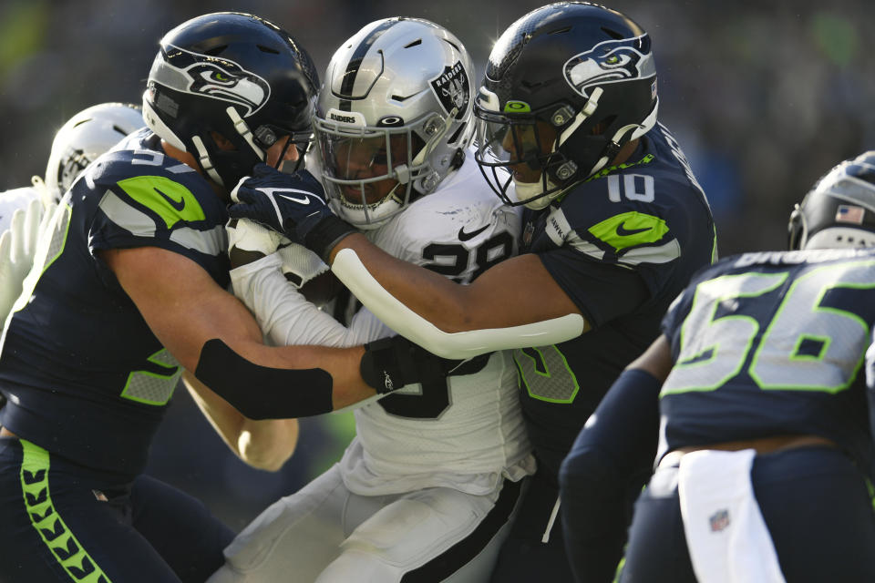 Las Vegas Raiders running back Josh Jacobs (28) is talked by Seattle Seahawks linebacker Uchenna Nwosu (10) during the first half of an NFL football game Sunday, Nov. 27, 2022, in Seattle. (AP Photo/Caean Couto)