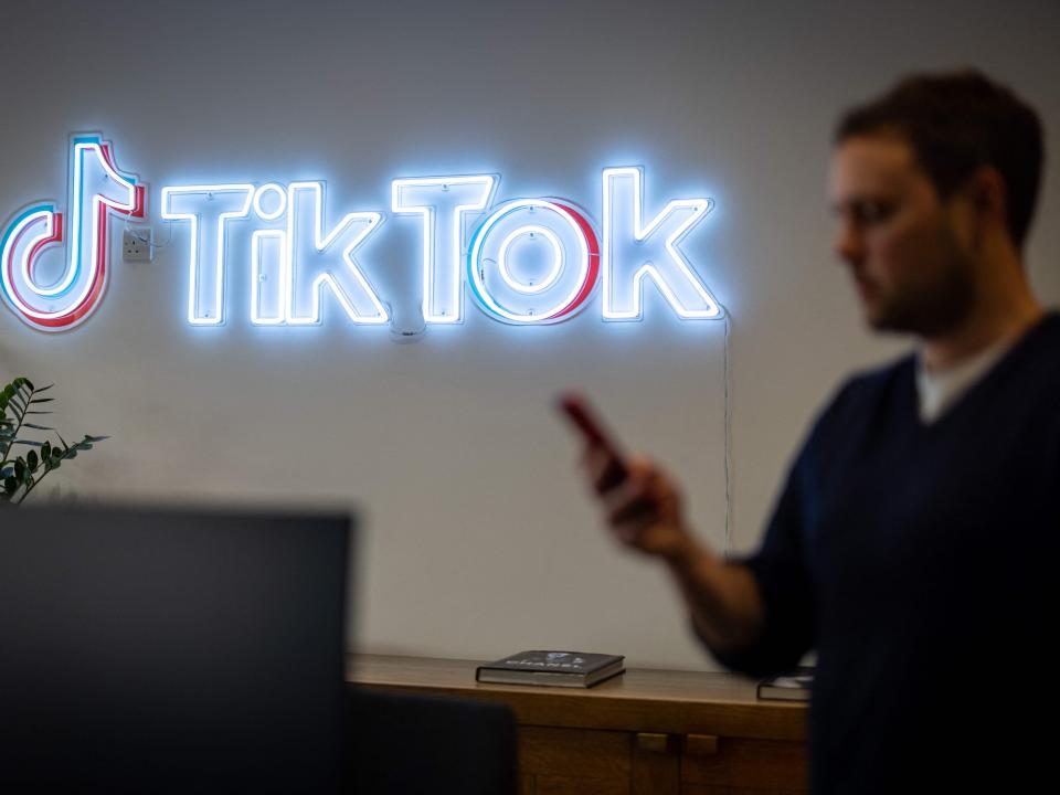 BuzzFeed News reported Monday that TikTok's owner ByteDance had scraped content from Instagram and Snapchat in 2017 to create fake accounts on Flipagram, TikTok's predecessor. Here, a TikTok employee looks at his mobile phone as he walks past the logo of TikTok in a London office on February 9, 2022.