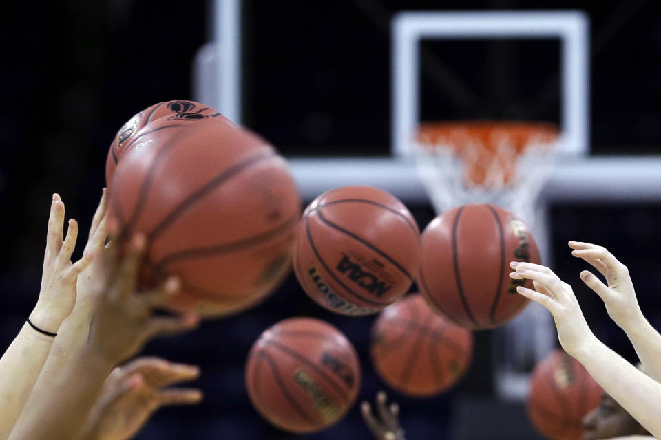 FILE - Athletes toss basketballs in a drill at practice at the women's NCAA college basketball tournament, Friday, March 29, 2013, in Spokane, Wash. The Supreme Court's decision to overturn Roe v. Wade has added another complicated layer for college coaches to navigate. And, for some coaches, the constantly shifting landscape is making their profession more demanding than ever. (AP Photo/Elaine Thompson, File)