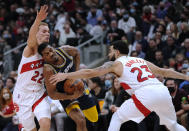 Memphis Grizzlies guard De'Anthony Melton (0) drives between Toronto Raptors guard Malachi Flynn (22) and guard Fred VanVleet (23) during the first half of an NBA basketball game Tuesday, Nov. 30, 2021, in Toronto. (Nathan Denette/The Canadian Press via AP)