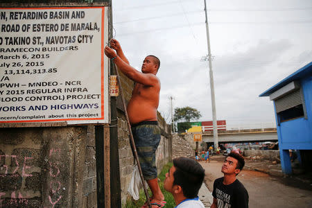 Local residents fix the street light that was broken near the C-3 bridge in North Bay Boulevard South (NBBS), a Navotas City district of slums and waterways with a high number of drug war deaths, in Manila, Philippines November 3, 2016. REUTERS/Damir Sagolj