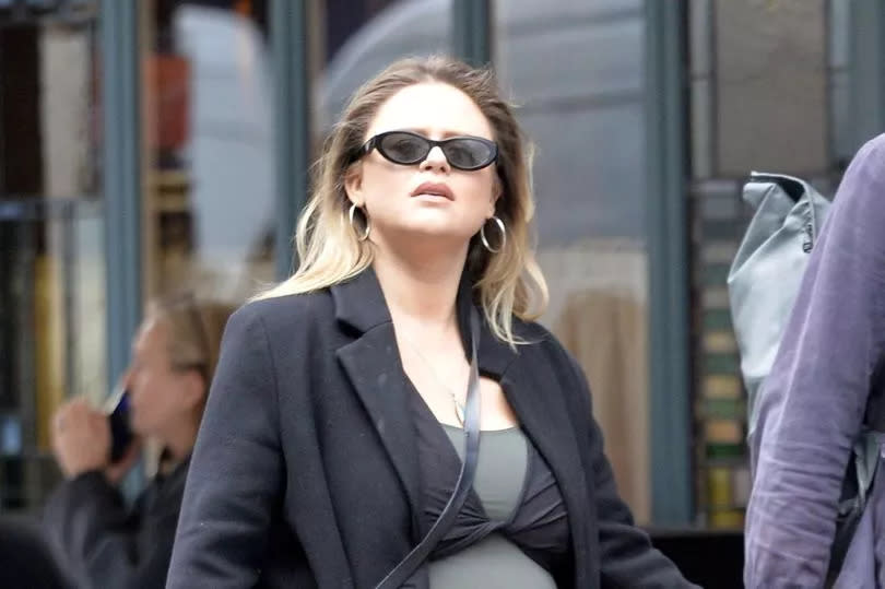 Emily showed off her blossoming baby bump in a figure-hugging top