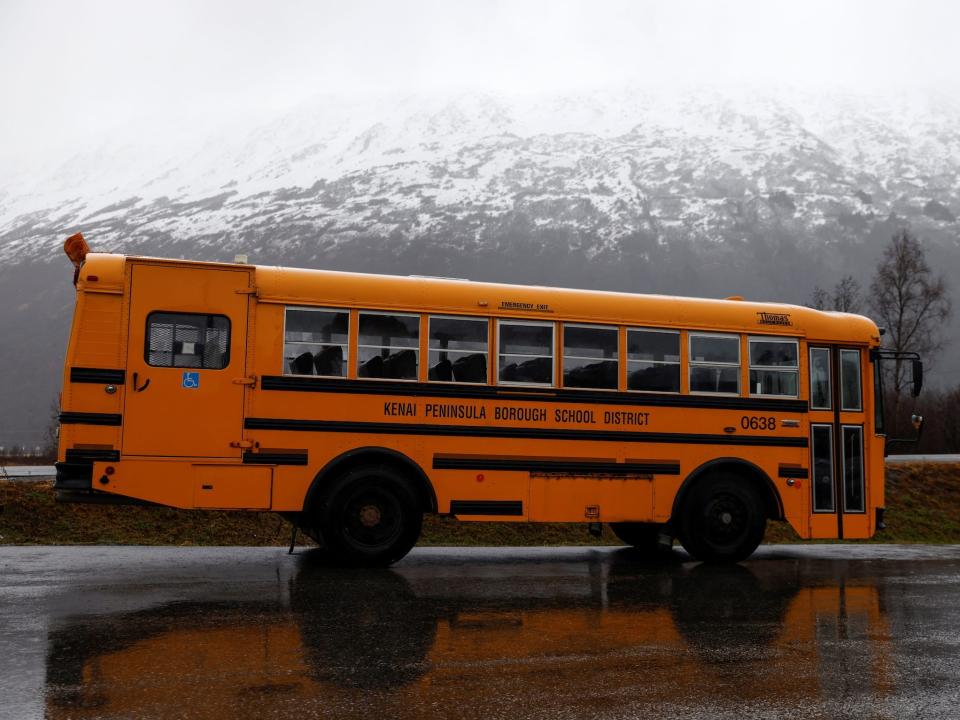school bus on rainy road against snowy mountain background