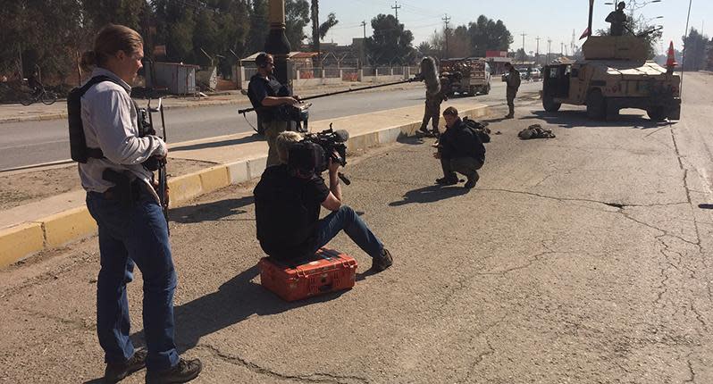 Filming, with three dead Islamic State fighters in the background