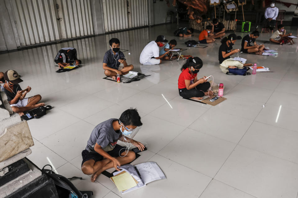 Students uses smartphones to work on online school assignments using free internet service while practicing physical distancing at a public hall in Ubung Kaja Village, Denpasar, Bali, Indonesia, on July 21. The Indonesian government has imposed a new normal era, but local authorities have still closed schools in high-risk areas.