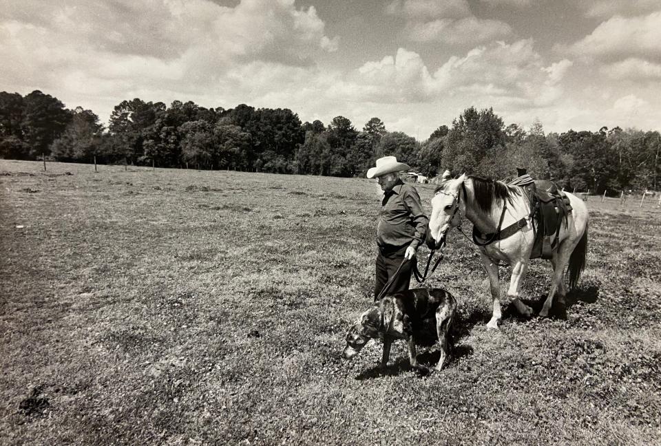 Jasper "Uncle Speedy" Solomon walks with his roping horse Bill in 1984 and his cattle-dog, also named Speedy, through a field near Ellis Road on the Westside, where a ranch house once stood.