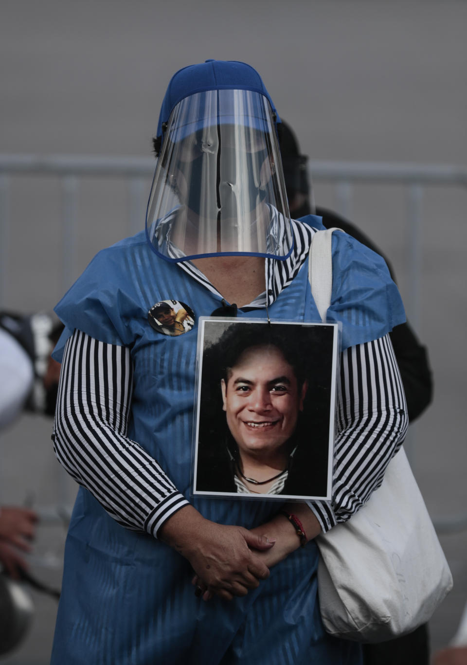 A woman wearing a mask amid the new coronavirus pandemic holds an image of a person who was disappeared, during a protest in front of the National Palace in Mexico City, Thursday, June 4, 2020. Relatives of different groups searching for the disappeared protested the cut to the budget destined for their search. (AP Photo/Eduardo Verdugo)