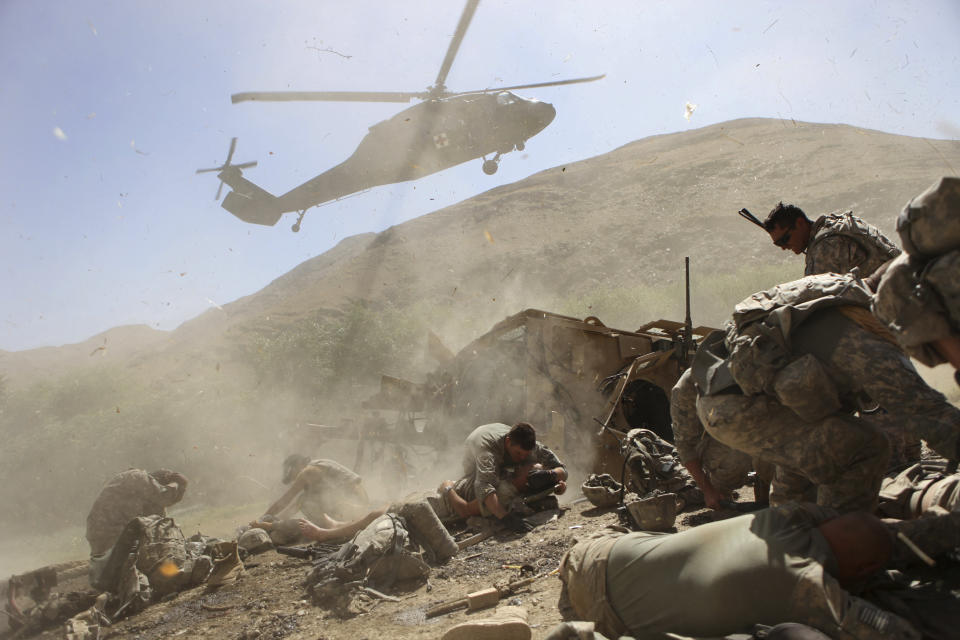 FILE - U.S. soldier Paul Pickett, 22, of Louisiana, center, covers wounded comrade James Gordon, 20, of Texas, to protect him from the rotor wash of a landing medevac helicopter at the Combat Outpost in Tangi Valley, Afghanistan, Aug. 19, 2009. (AP Photo/David Goldman, File)