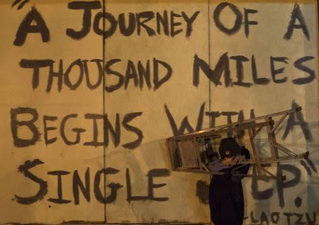 A boy carries a ladder past a quote by Chinese philosopher Laozi as he and other residents painted murals over boarded-up businesses in Ferguson, Missouri November 27, 2014. REUTERS/Adrees Latif