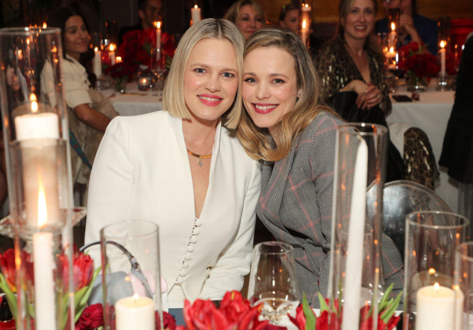 Kayleen and Rachel posing together, seated at an event table decorated with candles and flowers