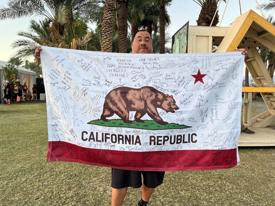 Leonard Ortiz displays his California state flag full of signatures from attendees around the globe during the Power Trip festival at the Empire Polo Club on Oct. 8, 2023.