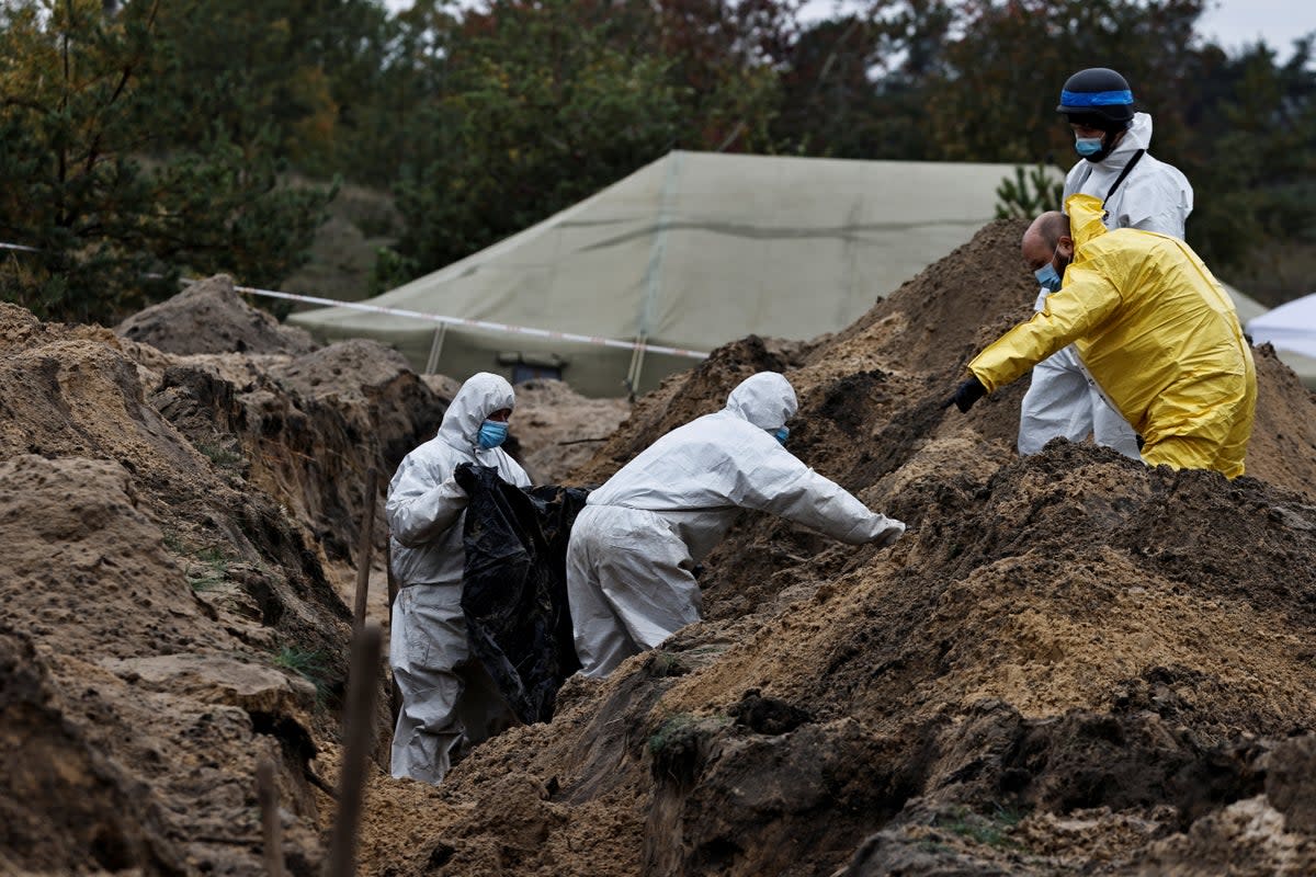 Investigators carry a body they exhumed from a mass grave in Lyman, Donetsk – an area that had been occupied by Russian forces until recently (REUTERS)