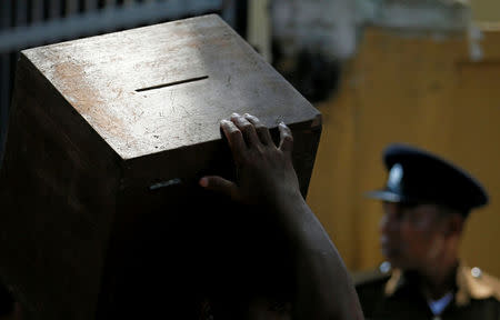 An electoral official carries a ballot box as he waits to get into a bus next to a police officer ahead of local government polls in Colombo, Sri Lanka February 9, 2018. REUTERS/Dinuka Liyanawatte