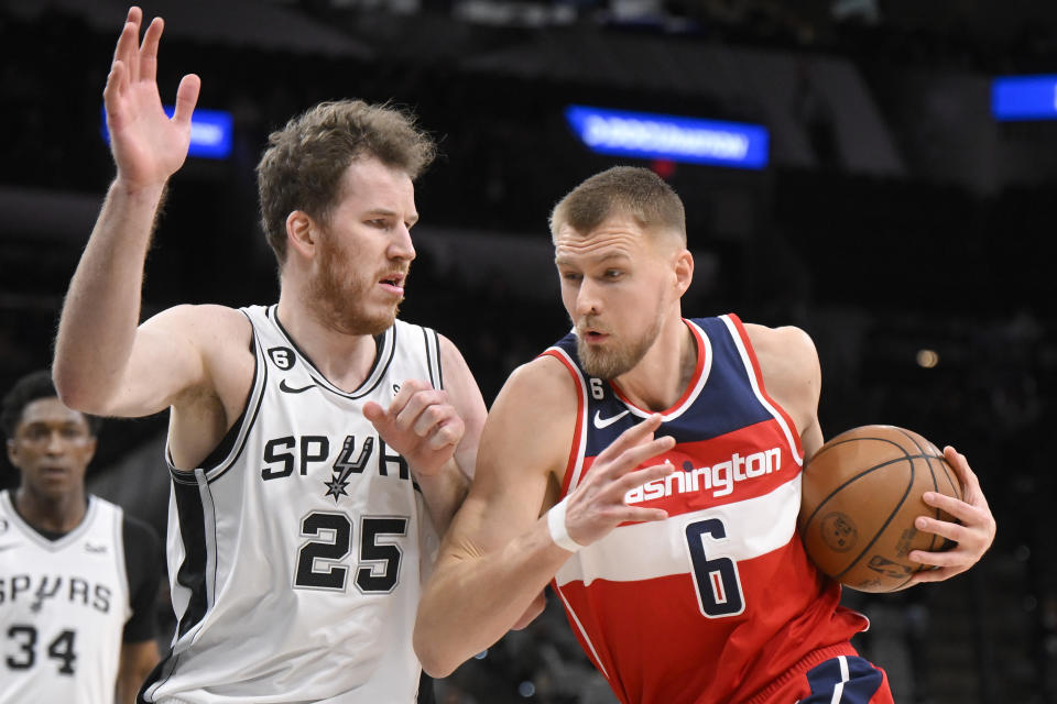 Washington Wizards' Kristaps Porzingis (6) drives against San Antonio Spurs' Jakob Poeltl during the second half of an NBA basketball game, Monday, Jan. 30, 2023, in San Antonio. (AP Photo/Darren Abate)