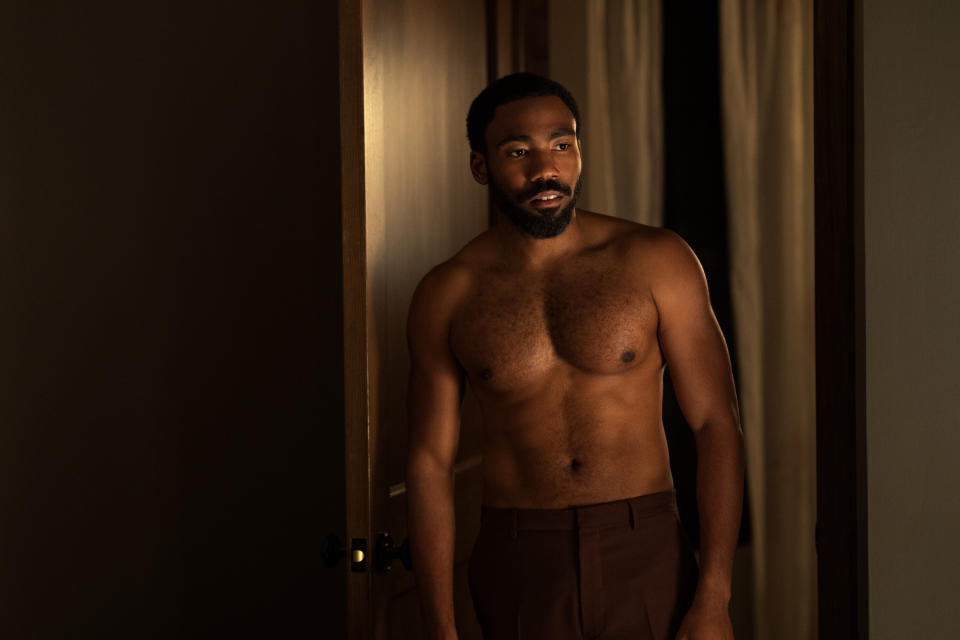 Donald Glover stands in a doorway topless in a scene from Mr and Mrs Smith