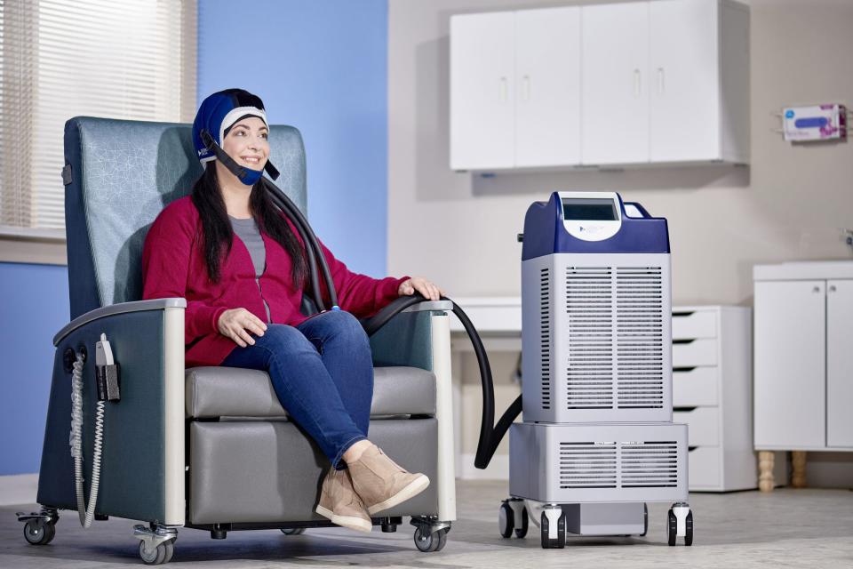 A scalp cooling cap is hooked into a proprietary machine – in this case one made by Dignitana – that circulates a cooling fluid around the scalp. A patient can be unhooked from the machine for short periods.