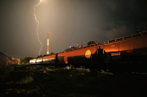 Central American migrants stand atop a freight train headed north early on August 4, 2013 in Arriaga, Mexico - Credit: John Moore/Getty Images