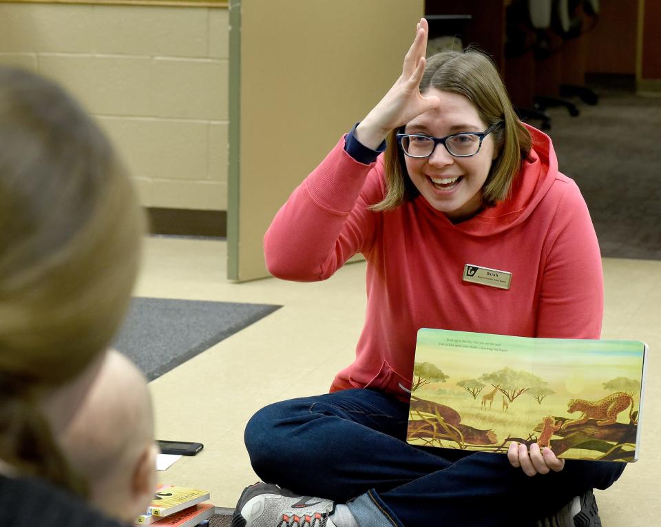 Sarah Seegert, the youth services technician at Summerfield-Petersburg Branch Library, goes over the words “Dada” (above) and “Mama,” which is off the chin, with the Zimmerman family at the sign language program.