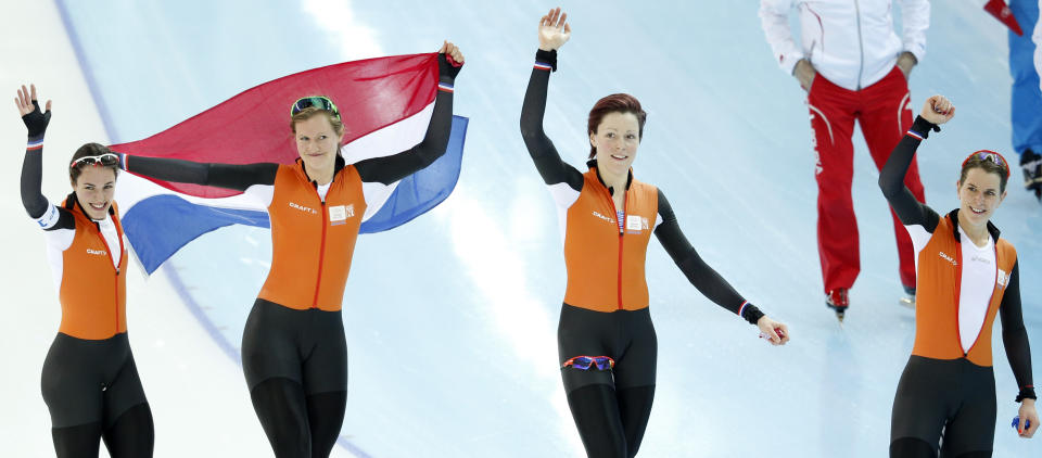 Marrit Leenstra, Lotte van Beek, Jorien ter Mors, and Ireen Wust of the Netherlands celebrate with the national flag after taking the gold medal on the women's team pursuit at the Adler Arena Skating Center at the 2014 Winter Olympics, Saturday, Feb. 22, 2014, in Sochi, Russia. (AP Photo/Pavel Golovkin)