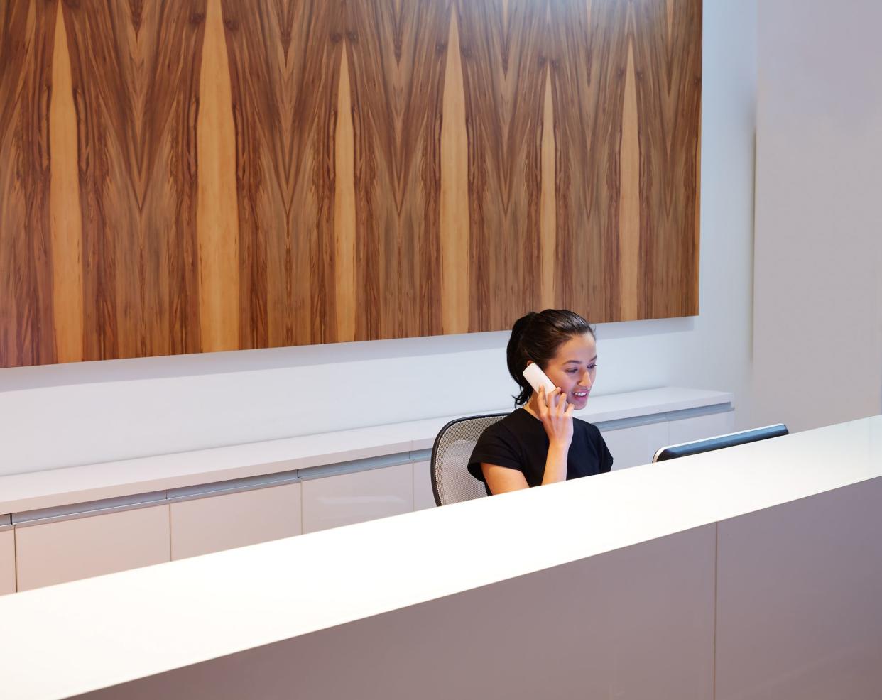 Brunette receptionist young woman in desk talking phone