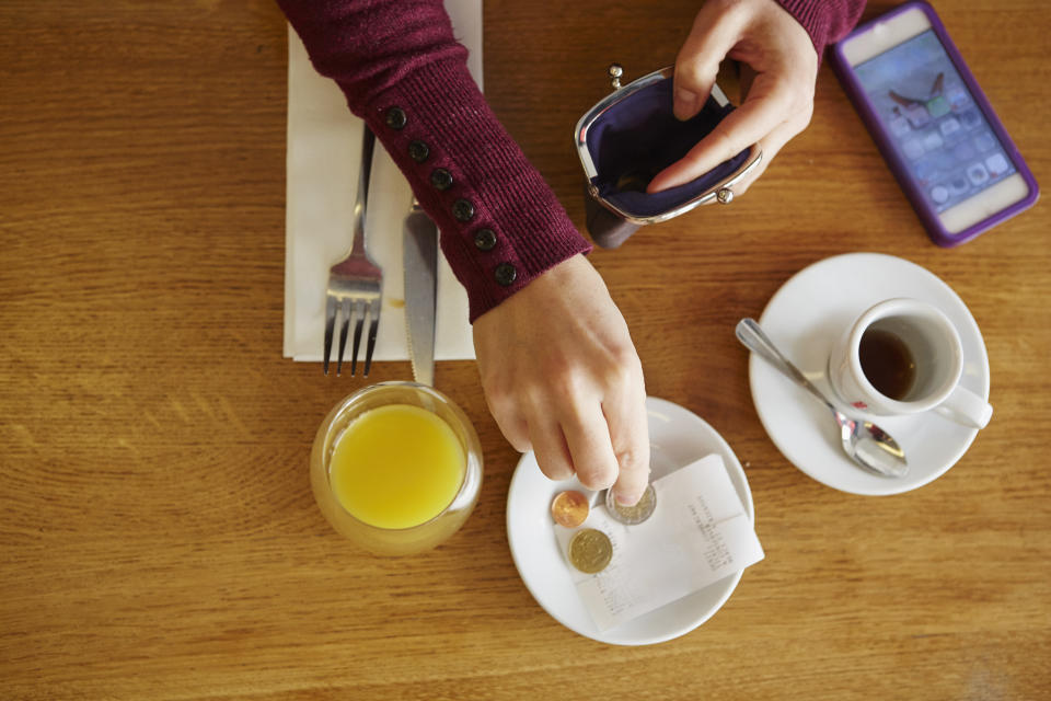 Overhead cropped view of woman leaving gratuity in restaurant