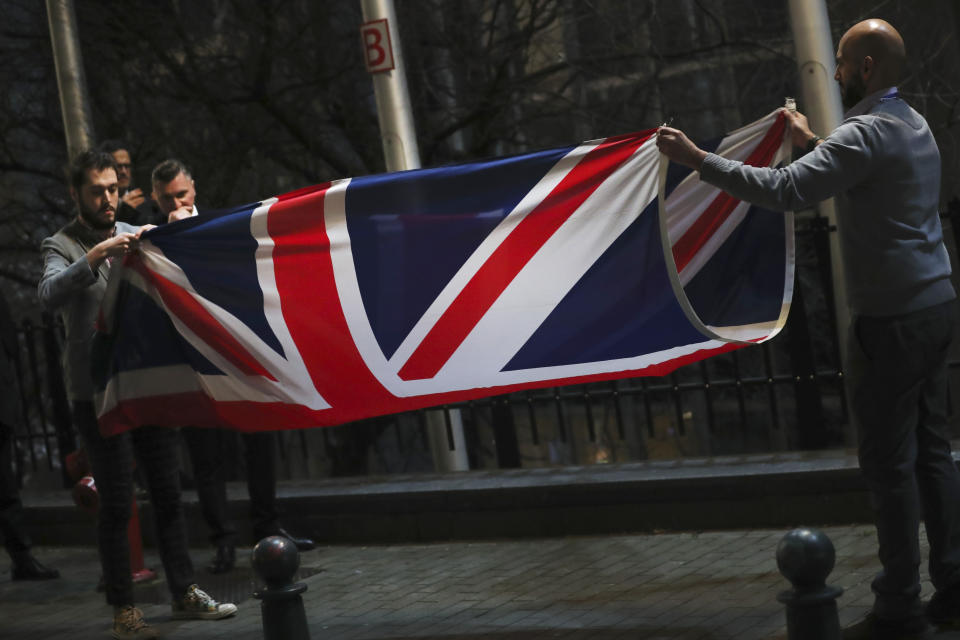 FILE -In this Friday, Jan. 31, 2020 file photo, the Union flag is folded and removed after being lowered from outside of the European Parliament in Brussels. It was late on Christmas Eve 2020 when the European Union and Britain finally clinched a Brexit trade deal after years of wrangling, threats and missed deadlines to seal their divorce. There was hope that now separated Britain and the 27-nation bloc would sail their relationship toward calmer waters. But, such was the bile and bad blood stirred up by the diplomatic brinkmanship and bitter divorce that, two months from another Christmas, insults of treachery and duplicitousness are flying again. (AP Photo/Francisco Seco, File)