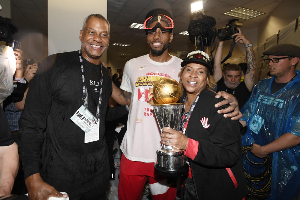 Toronto Raptors forward Kawhi Leonard poses with his uncle Dennis Robertson as his mother, Kim Robertson, holds his Finals MVP Trophy after the Raptors defeated the Golden State Warriors 114-110 in Game 6 of basketball's NBA Finals in Oakland, Calif., Thursday, June 13, 2019. (Frank Gunn/The Canadian Press via AP)