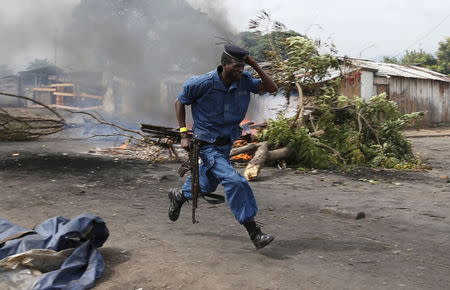 A policemen runs as protesters throw stones during a protest against Burundi's President Pierre Nkurunziza and his bid for a third term in Bujumbura, Burundi, May 22, 2015. REUTERS/Goran Tomasevic