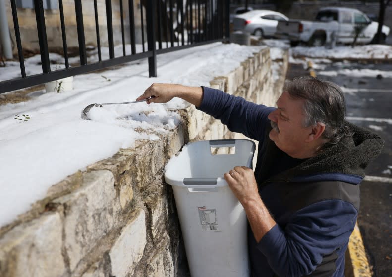 AUSTIN, TEXAS - FEBRUARY 19: Mark Maybou scraps snow into a bucket to melt it into water on February 19, 2021 in Austin, Texas. Mr. Maybou was using the water to flush his toilets since his home has no running water. Winter storm Uri brought historic cold weather causing people to lose their water as pipes broke throughout the area. (Photo by Joe Raedle/Getty Images)