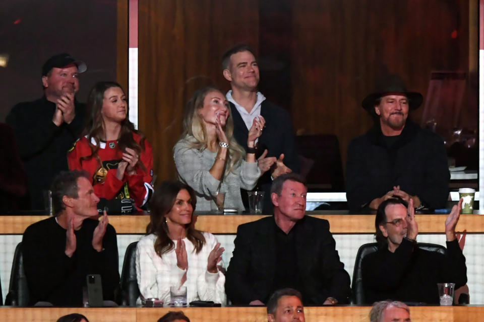 Musician Eddie Vedder top right, former Chicago Cubs president Theo Epstein top second from right, and model Cindy Crawford bottom second from left, clap during former Chicago Blackhawks great Chris Chelios' ceremony to retire his jersey before an NHL hockey game between the Chicago Blackhawks and Detroit Red Wings Sunday, Feb. 25, 2024, in Chicago. (AP Photo/Paul Beaty)