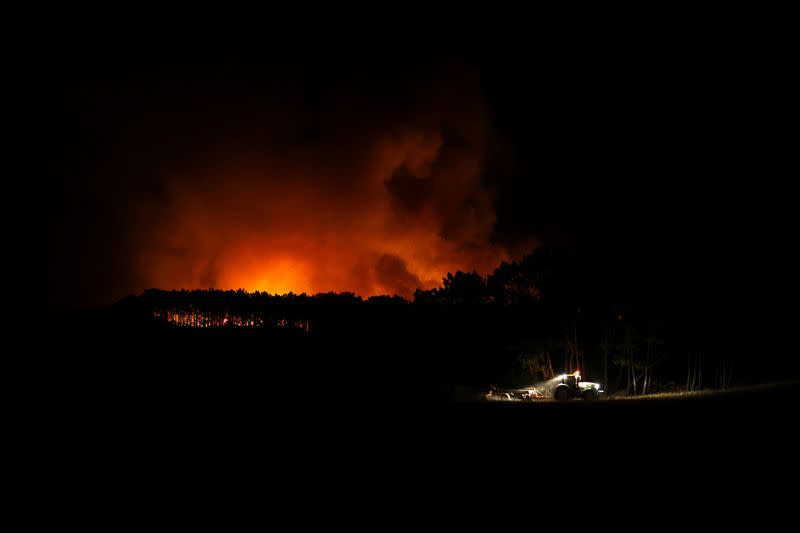 A tractor cleans up land during a wildfire in Aljesur