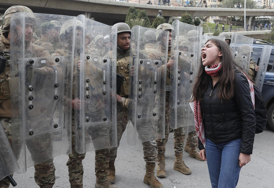 A protester shouts slogans in front of army soldiers during a protest against a parliament session vote of confidence for the new government in downtown Beirut, Lebanon, Tuesday, Feb. 11, 2020. Clashes broke out Tuesday between Lebanese protesters and security forces near the parliament building in central Beirut, where the new Cabinet is scheduled to submit its policy statement ahead of a vote of confidence. (AP Photo/Hussein Malla)