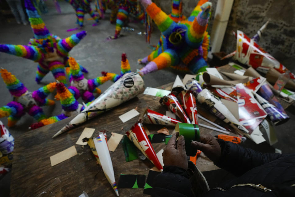 Un artesano de piñatas trabaja una con la forma tradicional, una esfera con siete picos, en un pequeño negocio familiar en Acolman, al norte de Ciudad de México, el miércoles 13 de diciembre de 2023. Esta artesanía tradicional tiene un origen religioso y está cargada de simbolismo: cada cono representa uno de los siete pecados capitales, por eso se golpea la piñata hasta destruirla como una forma de alejarse de esos pecados. (AP Foto/Fernando Llano)