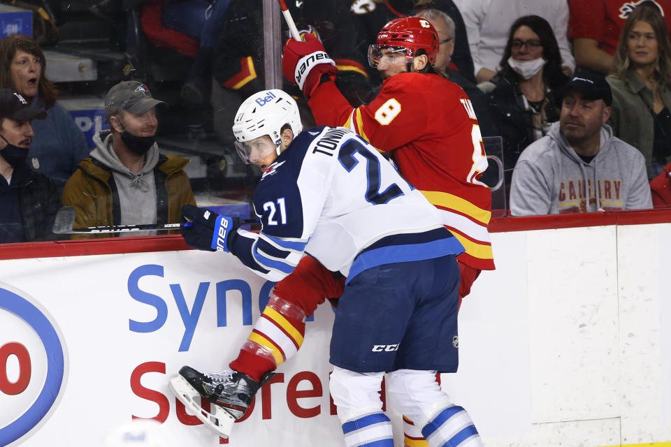 Winnipeg Jets' Dominic Toninato hits Calgary Flames' Christopher Tanev during the first period of an NHL hockey game Saturday, Nov. 27, 2021, in Calgary, Alberta. (Larry MacDougal/The Canadian Press via AP)