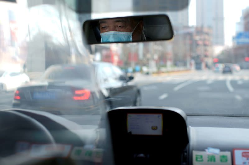 FILE PHOTO: A taxi driver wears a mask as he drives on a street in Shanghai